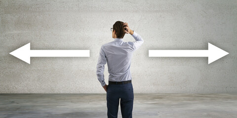 Poster - Back view of thoughtful young businessman with two pointers on concrete background, deciding which way to go. Decision and way concept.