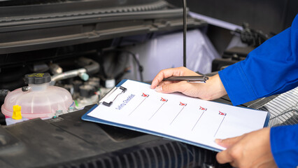 Wall Mural - action of a mechanic worker in blue uniform is using a pen to checking on safety checklist form to v