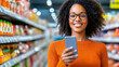 © Tanya - Happy smiling African woman with curly hair in glasses and orange jumper shopping in supermarket and use smartphone for help.
