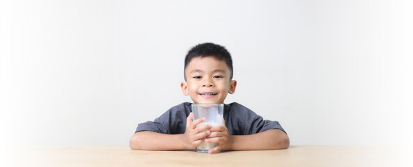 Asian child drinking milk on white background. Smiling of Asian boy with a glass of milk.