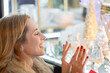 © Paula - Close-up shot of a happy and amazed woman in front of a Christmas shop window. She is looking enthralled and excited at the Christmas decoration in the store window.