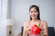 © amnaj - Young asian woman is smiling while holding a red bell pepper, promoting the benefits of a healthy lifestyle