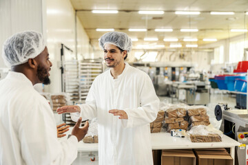 Two multicultural managers discussing food quality at food factory.