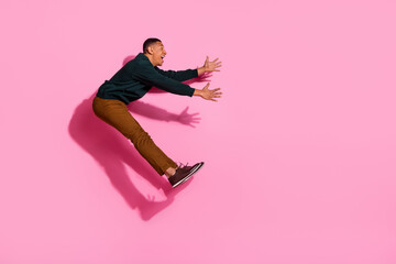 Poster - Full length photo of handsome good mood guy wear sweatshirt jumping high holding arms emtpy space isolated pink color background