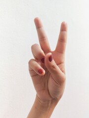 a woman's hand shows two fingers the peace symbol on a white background