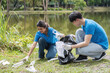 © wichayada - Young Volunteer Couple Collecting Trash in a Park to Promote Environmental Conservation and Community Cleanliness