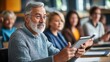 © keetazalay - In a peaceful adult learning center, seniors are attentively following along in a technology class, each with a tablet in hand, the instructor patiently explaining the steps, their expressions a mix