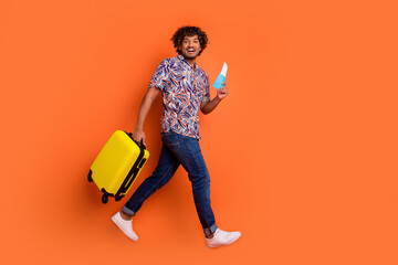 Sticker - Full length photo of handsome young man walk luggage hold tickets dressed stylish colorful garment isolated on orange color background