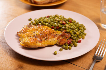 Wall Mural - Fried boneless skinless chicken leg with green peas for garnish on plate