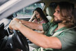 © SHOTPRIME STUDIO - Young couple in a car showing stress, with woman holding her head and man focused on driving