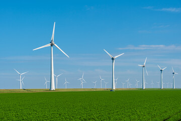 Wall Mural - Tall wind turbines spin gracefully against a bright blue sky, harnessing renewable energy while overlooking verdant farmland. Windmill park generating green energy electricity in the Netherlands