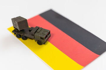 Wall Mural - War, military threat, military power concept. Germany. Tanks toy near German flag on black background top view