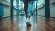 © COK House - A person in blue jeans and white sneakers walks in a hospital hallway with beds visible. Photo focuses on lower legs in mid-stride.