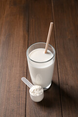 Wall Mural - Delicious protein shake in glass and scoop with powder on wooden table