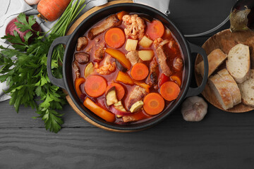 Wall Mural - Tasty homemade stew with vegetables and bread on grey wooden table, flat lay