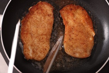 Canvas Print - Schnitzels cooking in frying pan on stove, top view