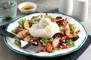 Plate with fresh burrata salad on grey textured table, closeup