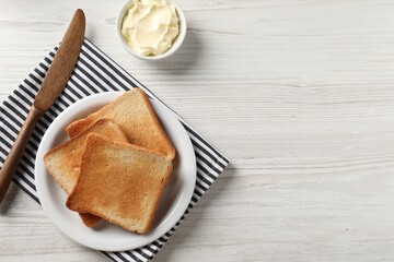 Wall Mural - Delicious toasted bread slices with butter and knife on white wooden table, flat lay. Space for text