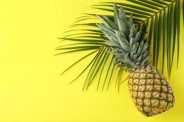 Wall Mural - Fresh ripe pineapple and palm leaf on yellow background, top view. Space for text