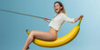 © www.freund-foto.de - Frau reitet Humorvoll übergroße Banane.  Lebendigen Farben erzeugt surrealen, komischen Effekt. Ideal für kreative, originelle Projekte