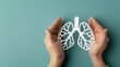 © pvl0707 - Hands gently holding a paper cut-out of lungs against a light blue background for World No Tobacco Day awareness campaign