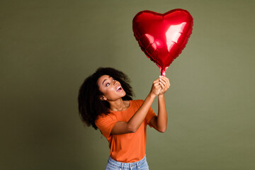 Sticker - Photo of adorable dreamy girl wear orange clothes rising heart balloon empty space isolated khaki color background