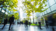 © Aksaka - Blurry silhouettes of people walking in a modern city setting