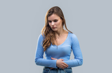 Girl with stomach ache on gray background. Woman holding stomach with both hands, the concept abdominal pain. Ache concept. Stomach pain and others stomach disease concept