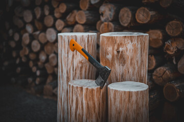 Axe cut in the chopping block in log trunks pile background. Lumber jacks wood cutting work tool.