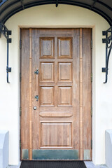 Beautiful old wooden door with iron ornaments of stone house. Wooden door with forged handle and stone wall