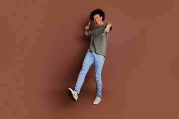 Sticker - Photo of youngster guy with wavy hair in gray t shirt and jeans casual outfit pointing fingers invites you party isolated on brown color background