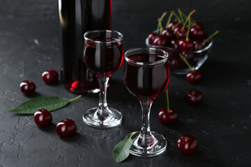 Delicious cherry liqueur and berries on black table