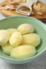 Wall Mural - Fresh raw potatoes in bowl on light grey table, closeup