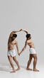 © Lustre Art Group  - Two men in white underwear form graceful, mirrored arch with their bodies, holding hands and leaning outward in perfect balance. Concept of male health, beauty and fashion, fitness, masculinity. Ad.