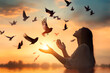 © john - Woman praying and free the birds flying on sunset background, hope concept