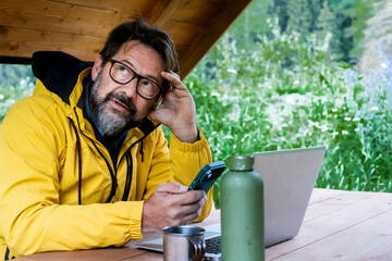 One mature handsome man thinking in outdoor modern leisure activity using phone and laptop. Modern traveler and technology for connection. Holding cellular outside. Traveler male with roaming data