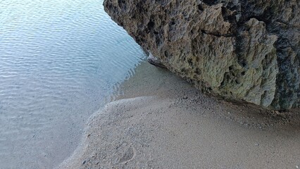 Wall Mural - A rock is on the beach next to the water