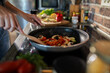 © Geber86 - Close-up of a woman cooking vegetables in a pan on the stove