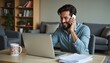 © AlgoVijo - Smiling Man on Phone While Working on Laptop at Home Office.