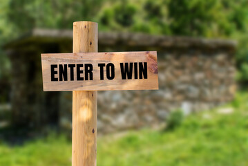 Enter to win message written on wooden sign with nature background. Conceptual enter to win symbol. Copy space.