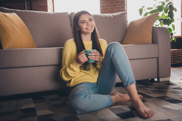 Wall Mural - Full length photo of teen lady sit floor couch drink tea look empty space dressed yellow garment spend pastime spacious house indoors room