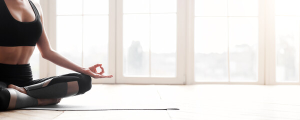 Wall Mural - Balance, meditation, relaxation concept. Cropped photo of fit woman meditating during yoga class over panoramic windows background, panorama with copy space