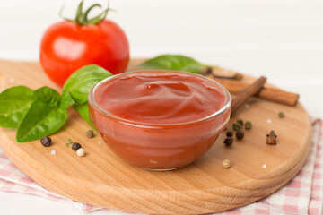 Delicious ketchup with spices and tomatoes on wooden table