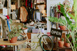© AnnaStills - Cozy retail space featuring various potted green plants and an open sign, creating inviting atmosphere with bicycles and shelves adding to the charm