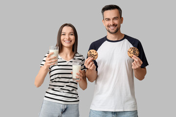 Wall Mural - Young couple with tasty cookies and glasses of milk on grey background