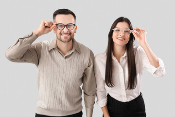 Young couple in eyeglasses on light background