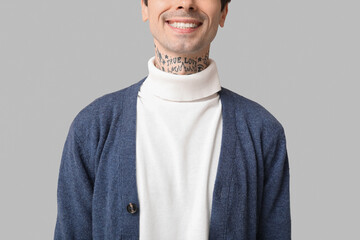 Sticker - Happy handsome young tattooed man on grey background, closeup