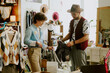 © AnnaStills - Two people engaged in sorting clothes in a vintage clothing store surrounded by various clothing items and accessories creating a well-organized setting