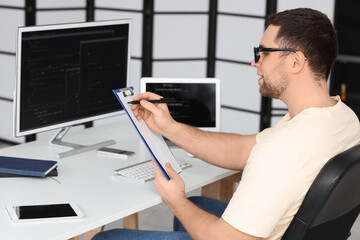 Wall Mural - Portrait of male programmer with clipboard in office