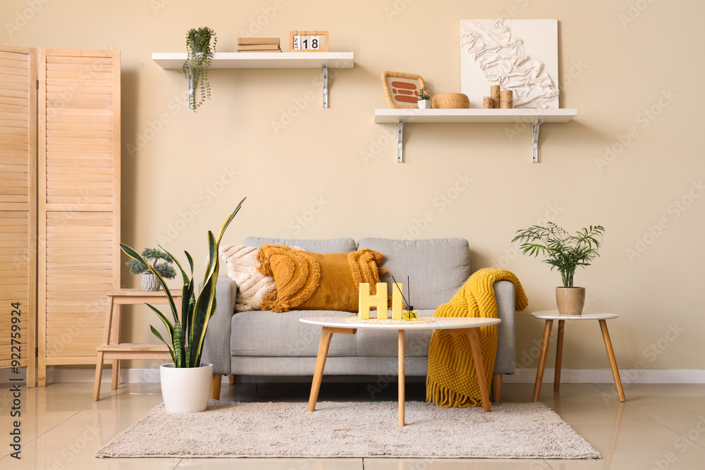 Aroma diffuser, decorative letters HI on table and comfortable sofa in interior of living room
